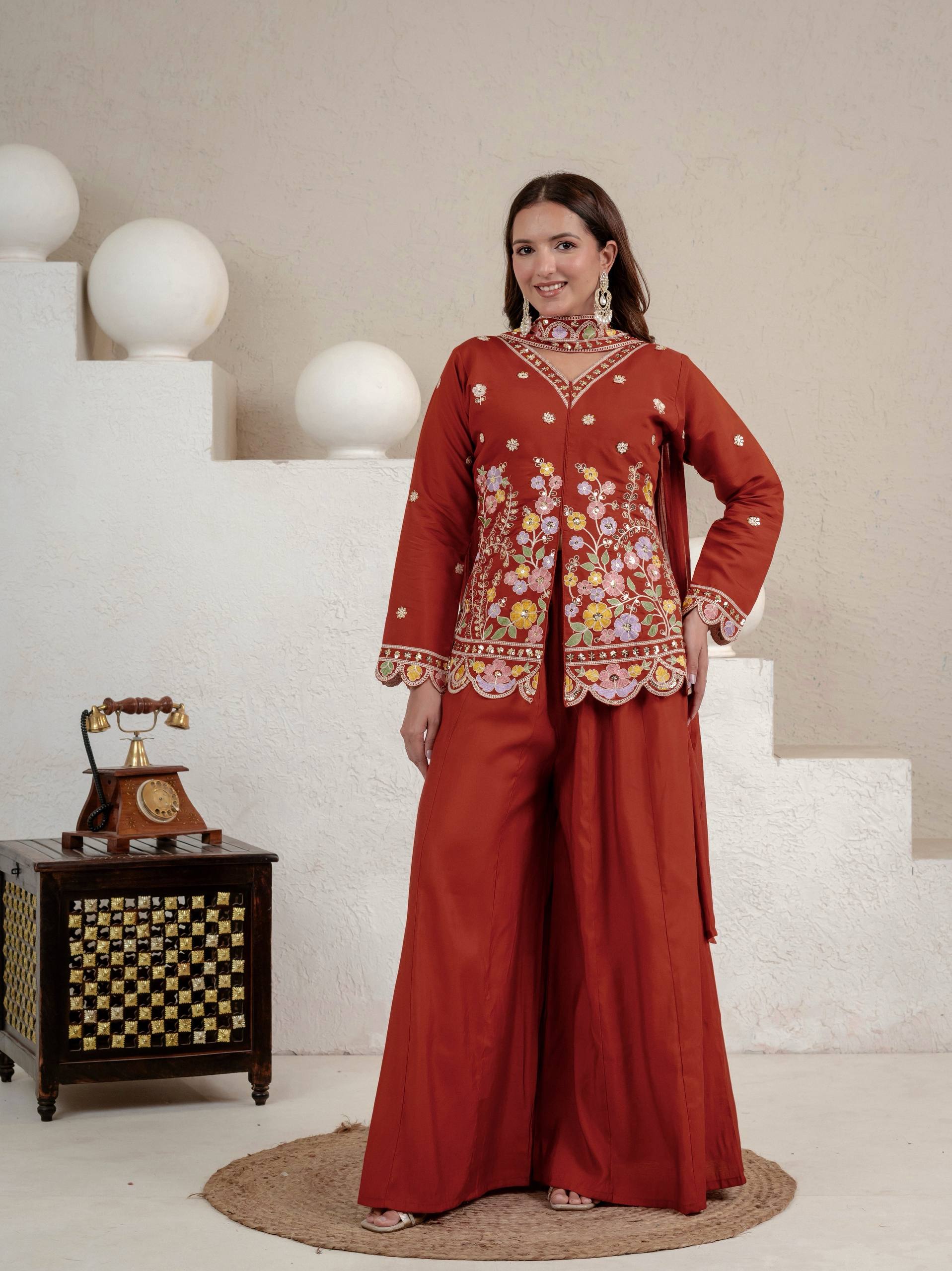 Resplendent Rust Orange Peplum Kurti and Flared Palazzo Suit Set Adorned with Intricate Multicolored Floral Embroidery, Sequin Accents, and Ornate Scalloped Borders